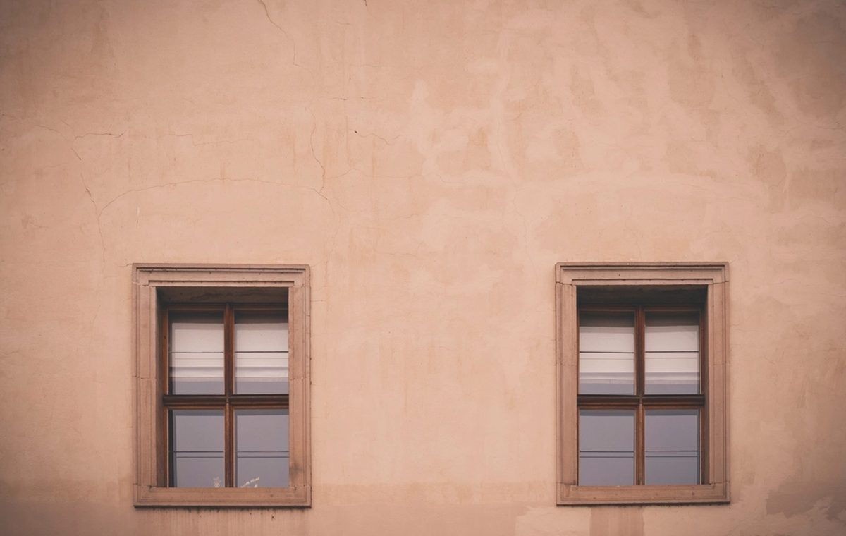 Verputzte Hausfassade in warmem Farbton mit zwei Fenstern